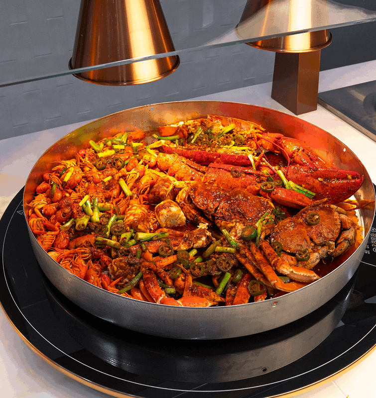 Spicy seafood boil with crab, lobster, and crawfish served in a large pan at an all-you-can-eat restaurant.